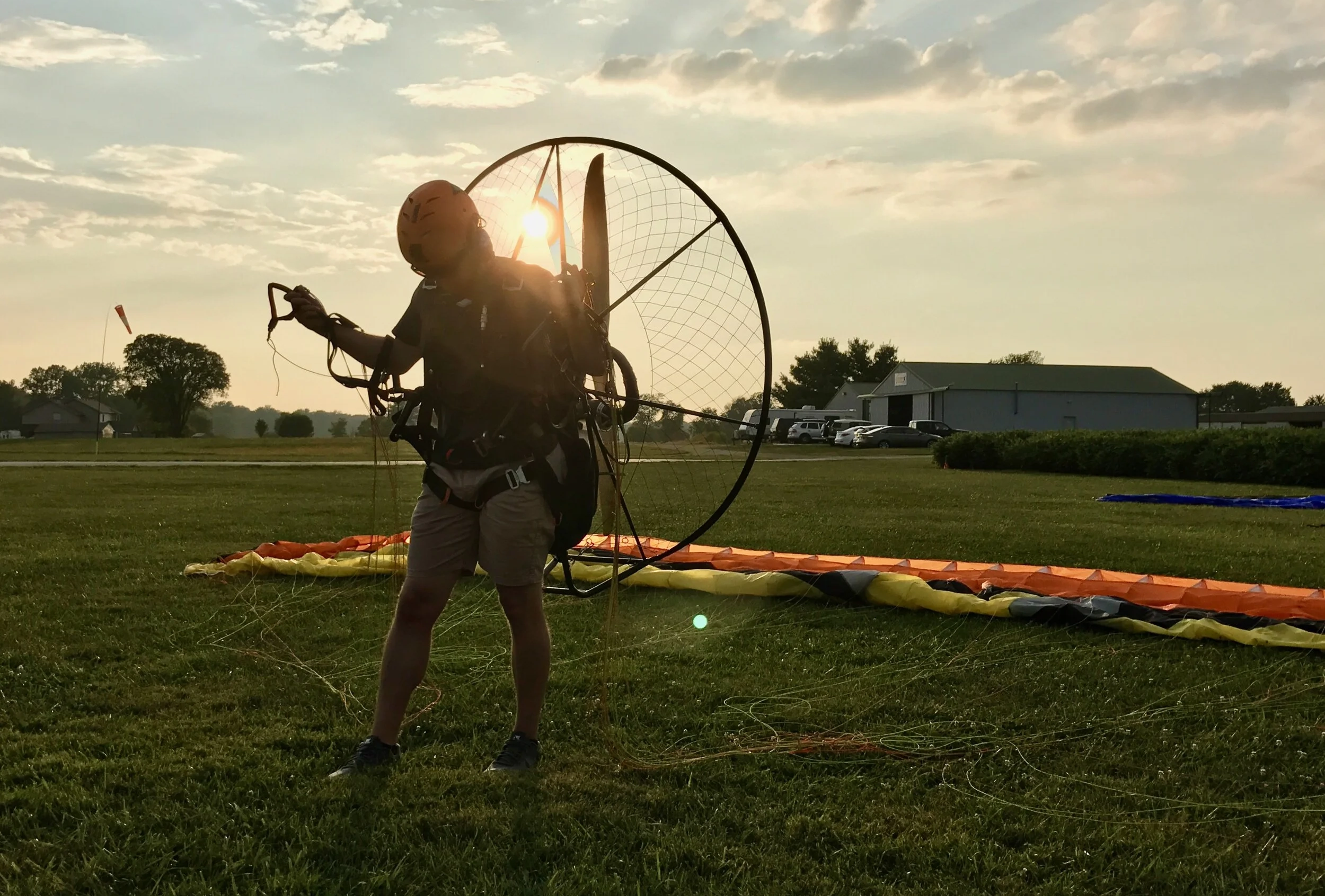 Pilot preparing to launch a paramotor with wing lines laid out in the grass